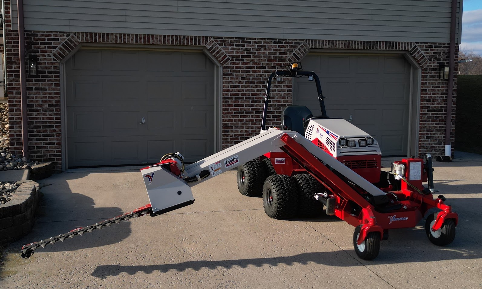 Our Ventrac using the boom mower attachment to trim a weeping-willow.