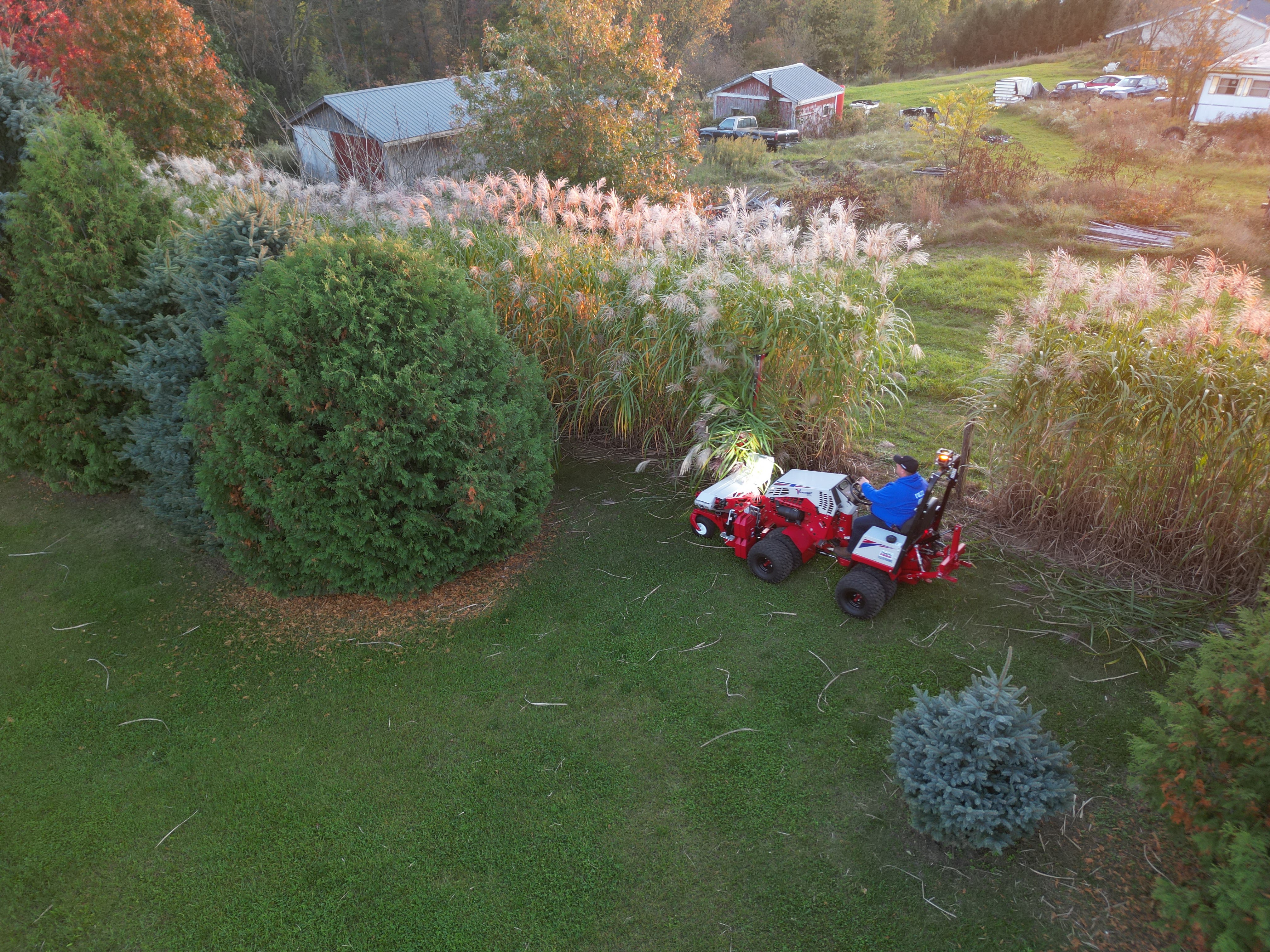 The tough cut services Ventrac mowing brush on a leaf-covered sloped bank.