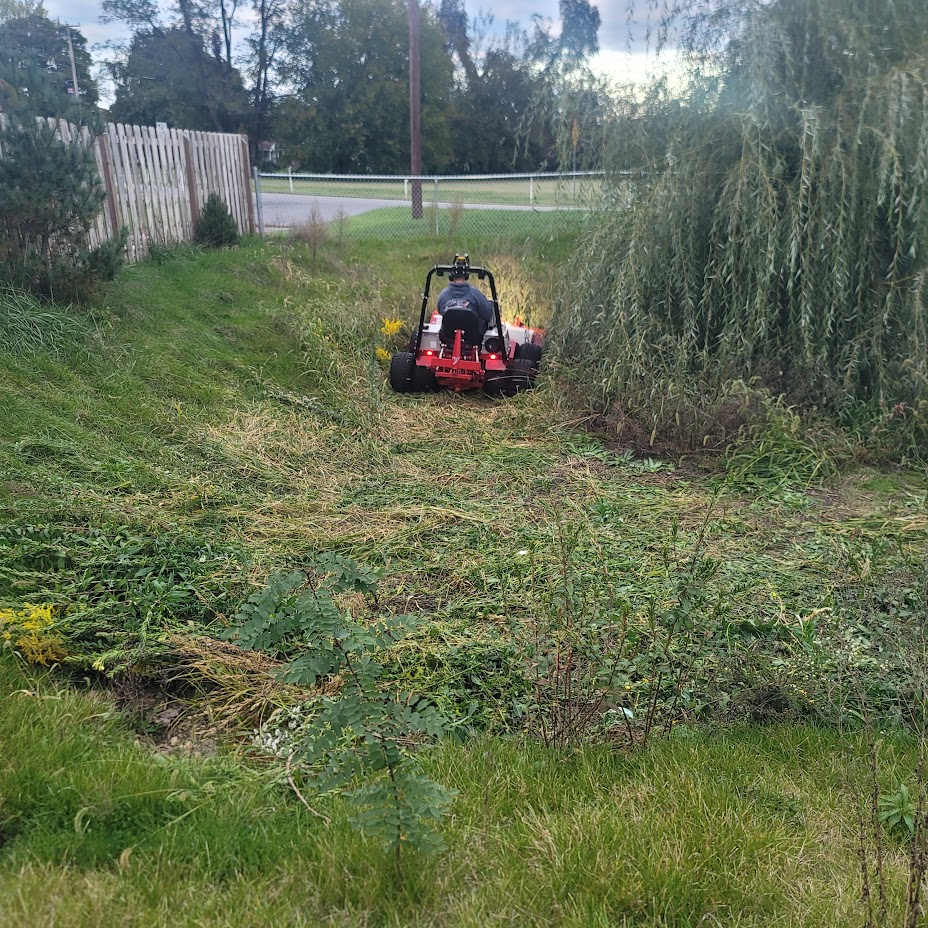 Our Ventrac mowing thick brush at the bottom of a water retention pond.